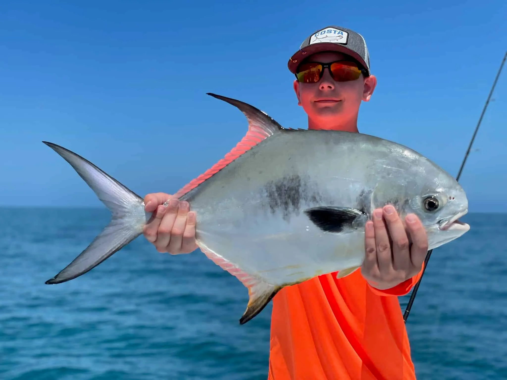 Young angler holding a large pompano on an offshore charter