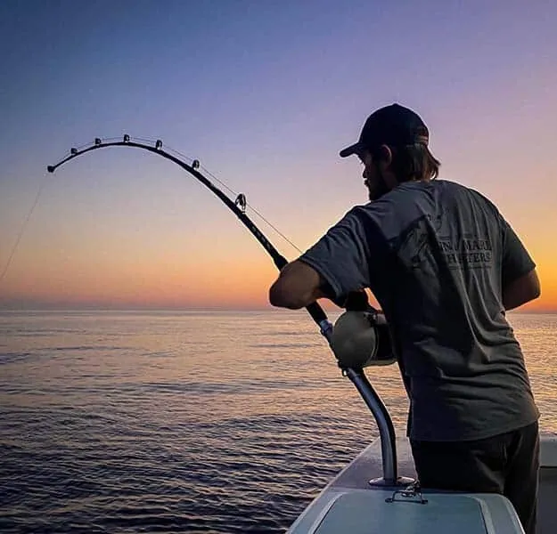 Angler reeling in a fish aboard an Anna Maria Charters boat